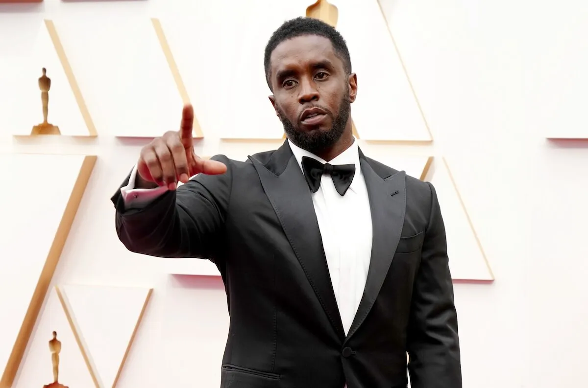 Sean 'Diddy' Combs wears a tuxedo and holds out his arm.